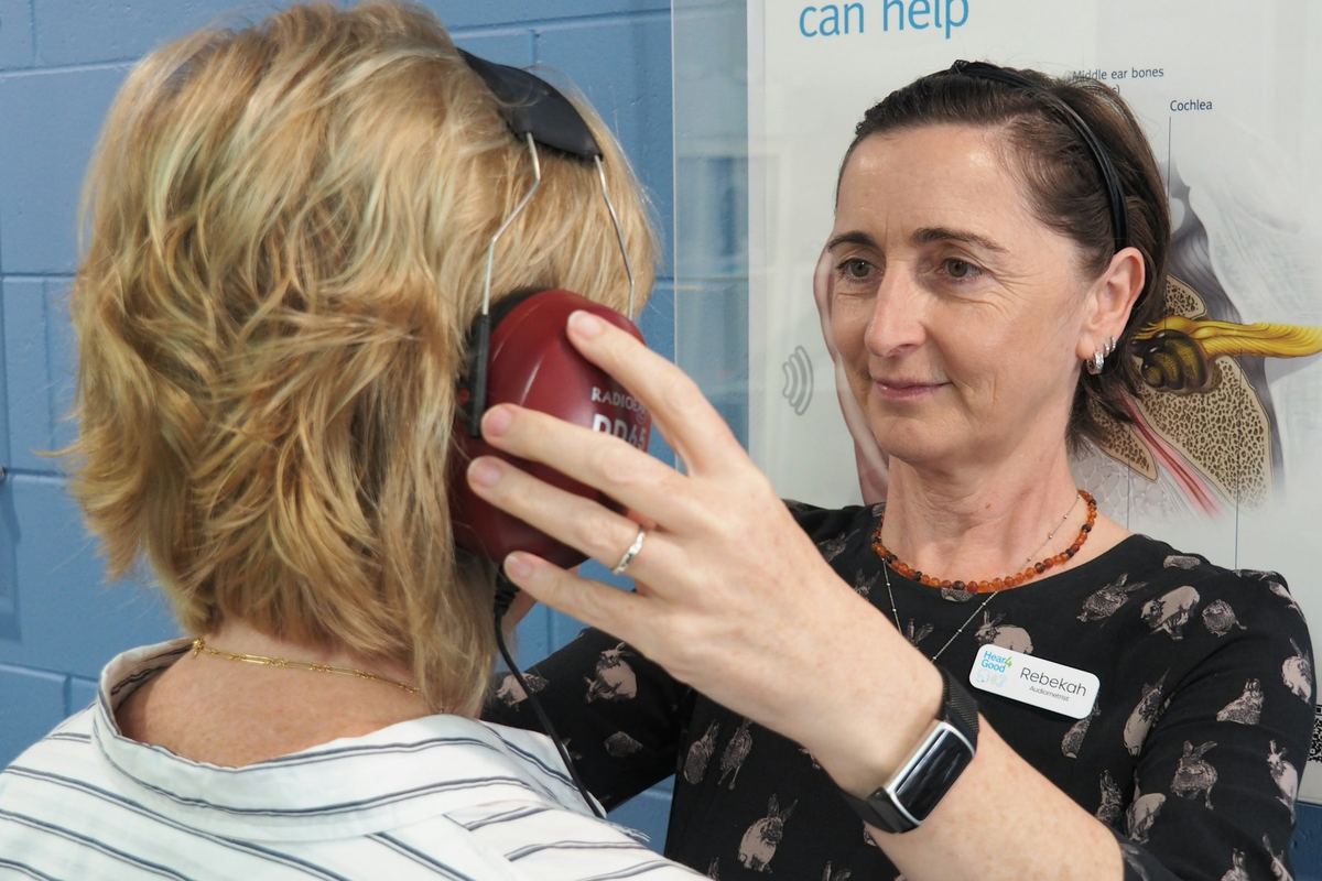 An audiologist fitting headphones for a hearing test
